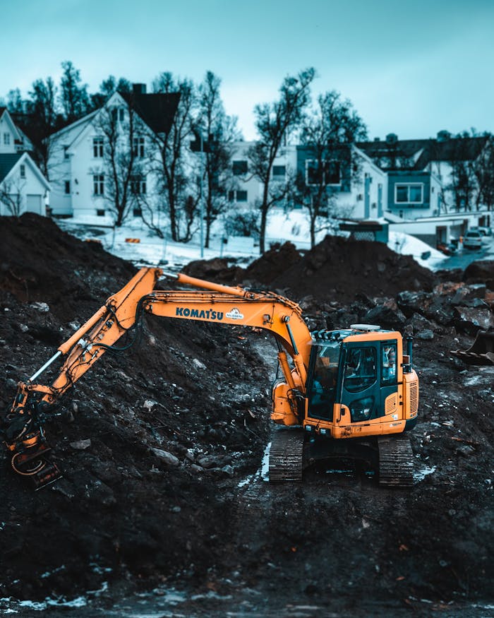 A powerful excavator operates at a Tromsø construction site during winter, showcasing heavy machinery.