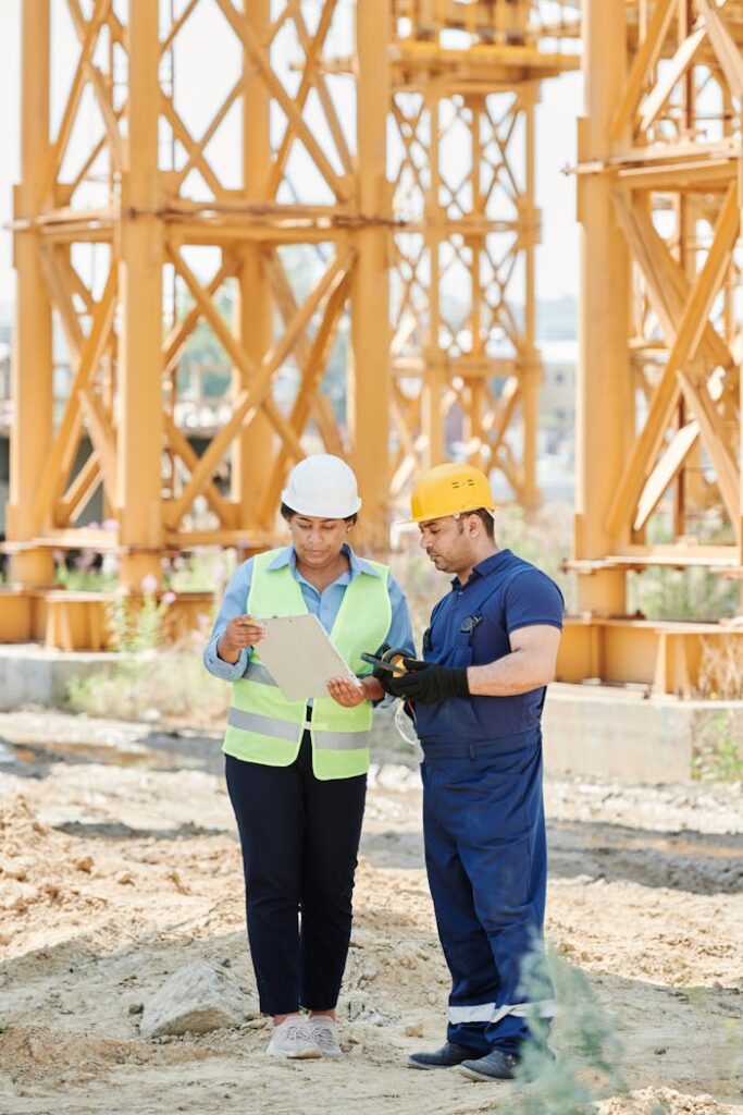 Two construction workers on site, discussing project plans with safety gear and hard hats.